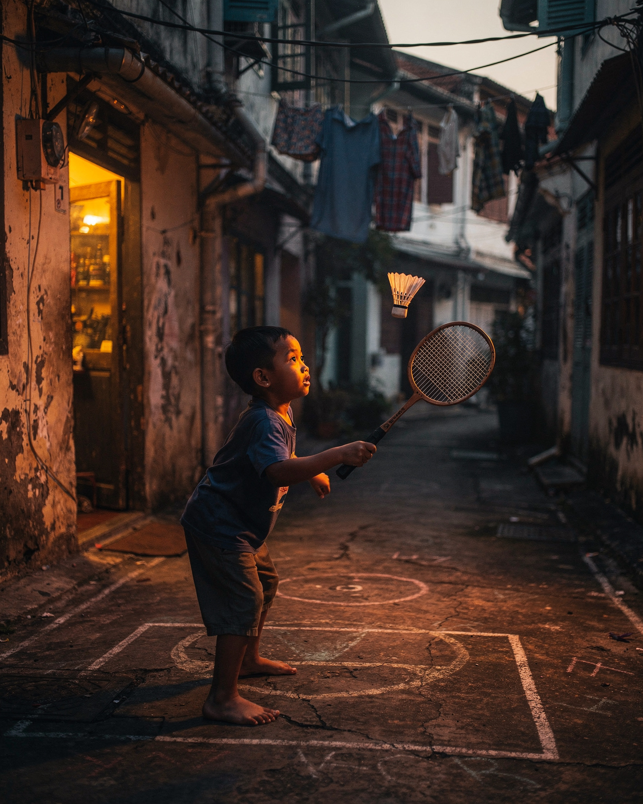 A boy playing badminton in a Penang alley